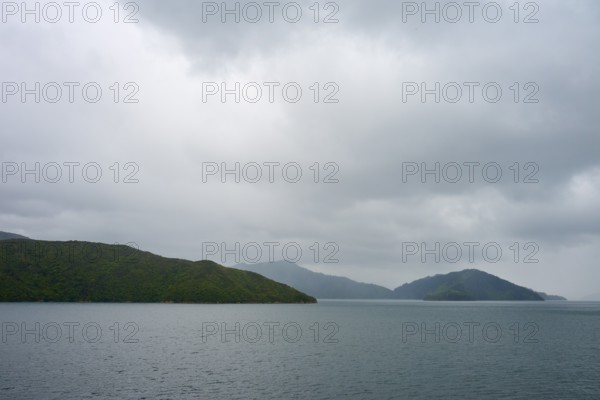 View of calm sea with cloudy sky and green islands, summer, Cook Strait, North Island, South