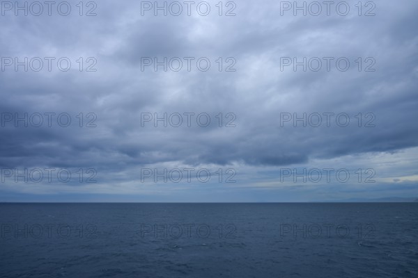 The sea stretches as far as the horizon under a cloudy sky, summer, Cook Strait, North Island,