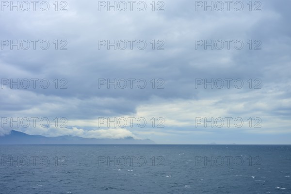 Wide sea with cloudy sky and distant mountains on the horizon, summer, Cook Strait, North Island,