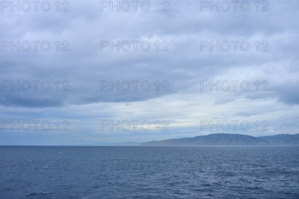 View of the sea and a distant coastline under a cloudy sky, summer, Cook Strait, North Island,