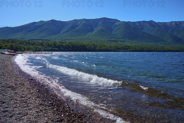 Beach with pebbles, waves crashing on the shore, peaceful mountain landscape, summer, Lake Rotoiti,