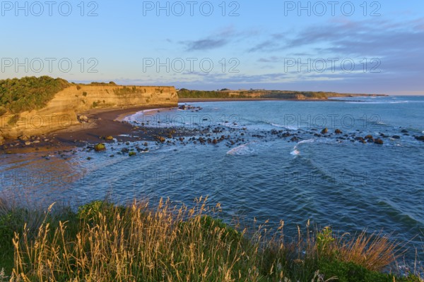 Idyllic coastal scene at sunrise with waves, beach and cliffs, summer, Opunake, Taranaki, North