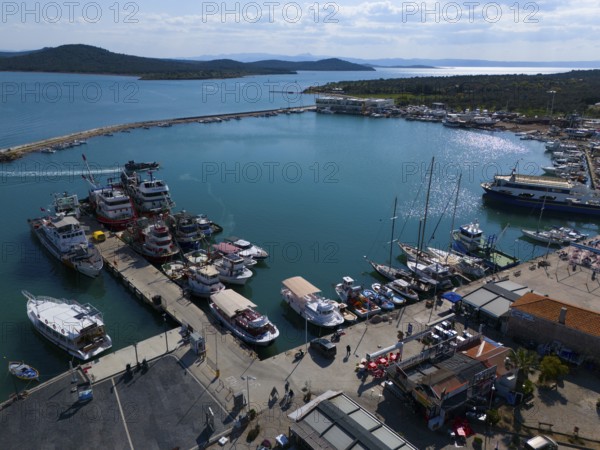 Sunny harbour with boats and yachts, surrounded by azure blue water and landscape, aerial view,