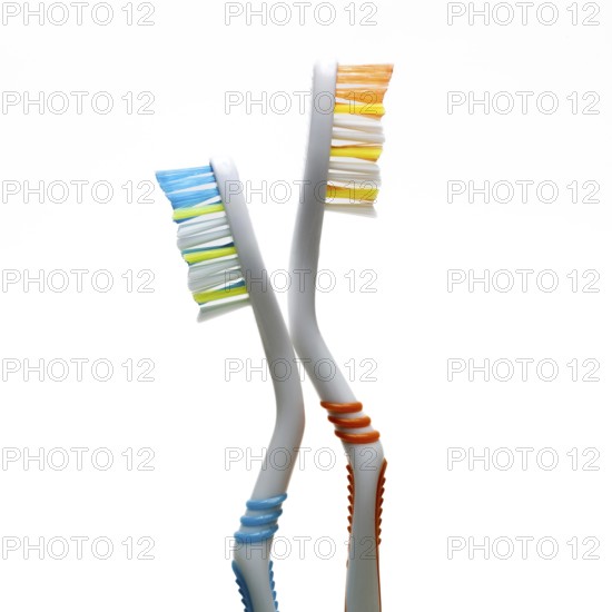 Two vibrantly colored toothbrushes stand at an angle against a plain background. They highlight the