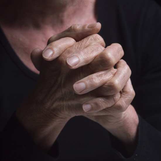 Fingers intertwined convey a sense of contemplation and tranquility. The soft lighting highlights