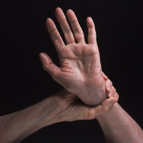 Two hands are featured in contrasting positions, highlighting the skin's texture and the grace of