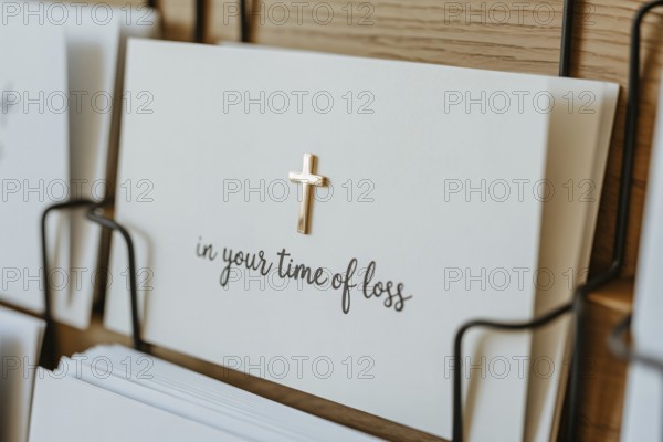 Clos eup of condolence card with In your time of loss text and religious cross displayed in a card