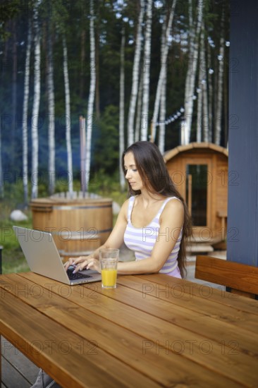 A woman finishes remote work while sitting on the terrace in the evening and is about to go to