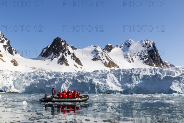 Zodiac in front of glacier and mountain range with snow, sea, Fugelfjorden, Spitsbergen, Svalbard