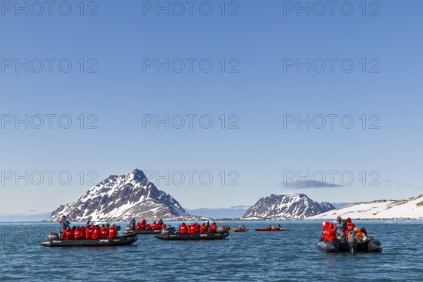 Group of Zodiacs in front of mountains with snow, sea, Fugelfjorden, Spitsbergen, Svalbard
