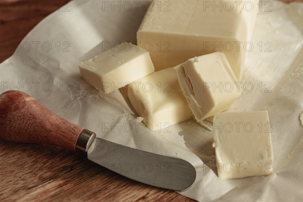 Butter briquette, on wrapping paper, wooden chopping board and butter knife, breakfast, rustic