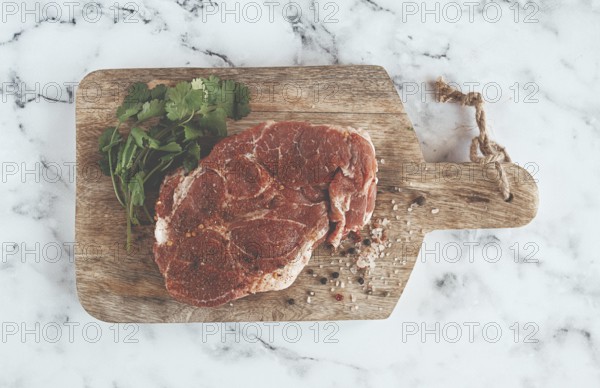 Raw pork steak, pork neck, on a chopping board, marble table, top view, with spices and coriander,