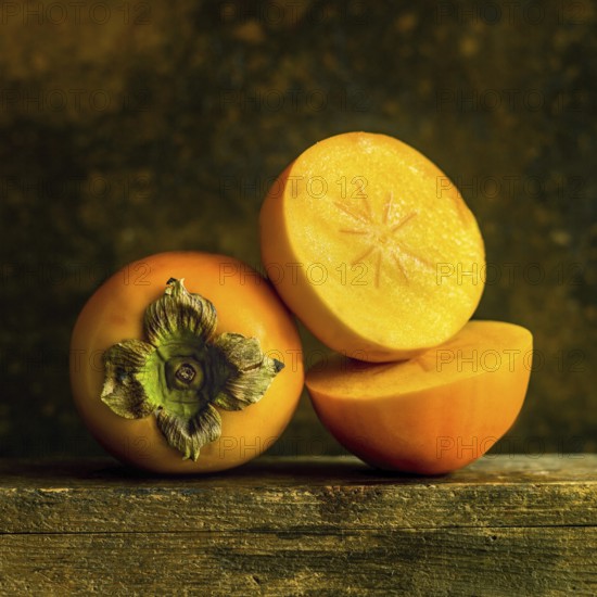 Ripe persimmons are arranged thoughtfully, displaying their smooth skin and bright orange flesh.
