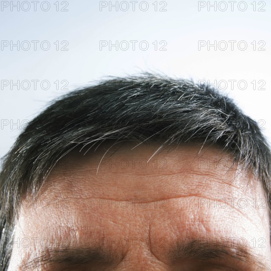 The view focuses on a man's forehead and hair, highlighting natural gray strands against a light