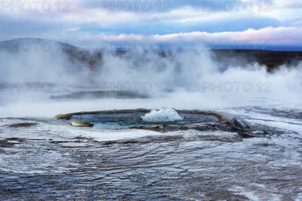 Sinter terraces with geyser, sulphur vapour, evening sky, Hveravellir geothermal area, Icelandic