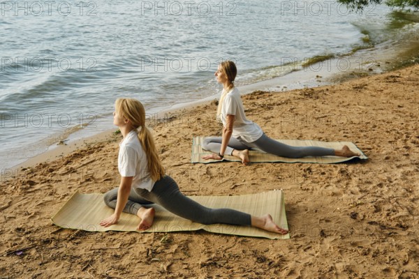 Practicing yoga poses by the serene lakeside at sunrise for relaxation and mindfulness