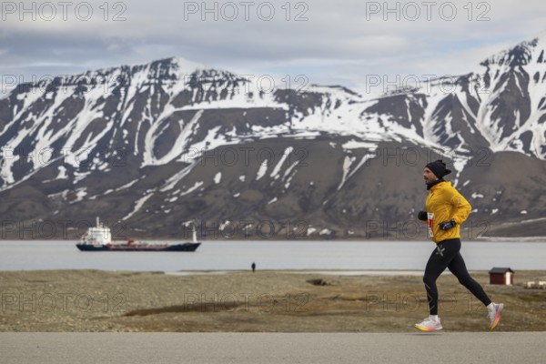 Marathon, runner in front of fjord with cargo ship, Adventtoppen, Longyearbyen, Spitsbergen,