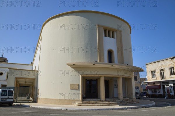 Cinema, A modern, round building with columns, cream-coloured façade under a clear blue sky,
