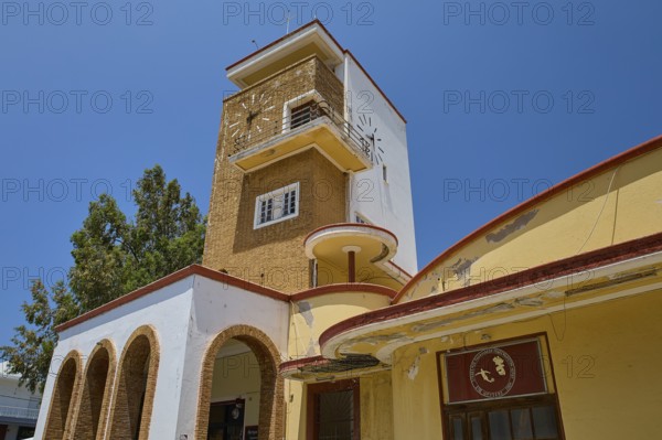 Market Hall, Agora, Historic Clock Tower with arches and surrounding trees under bright sunshine,