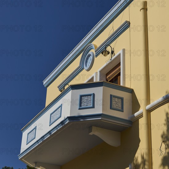 Yellow building with decorative balcony in front of a clear blue sky, Armando Bernabiti,