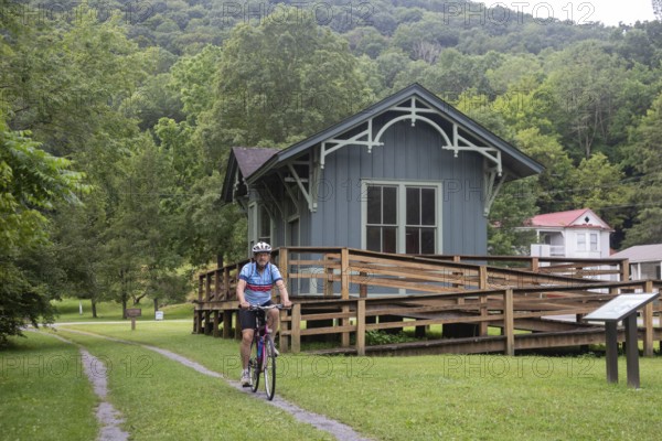 Clover Lick, West Virginia - A bicyclist rides past a restored train station on the Greenbrier