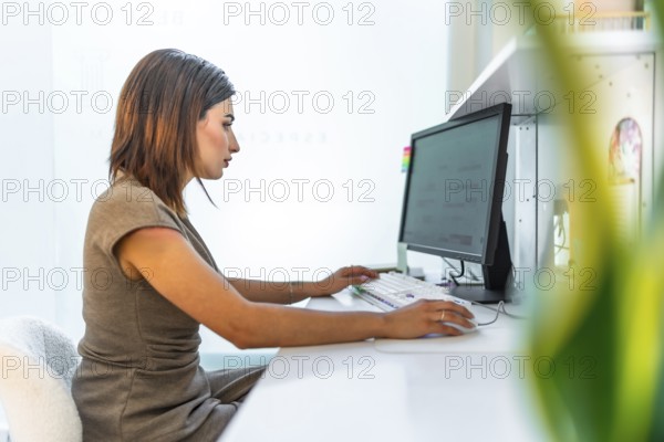 Beautician using a desktop computer, managing appointments and customer data in a bright and modern