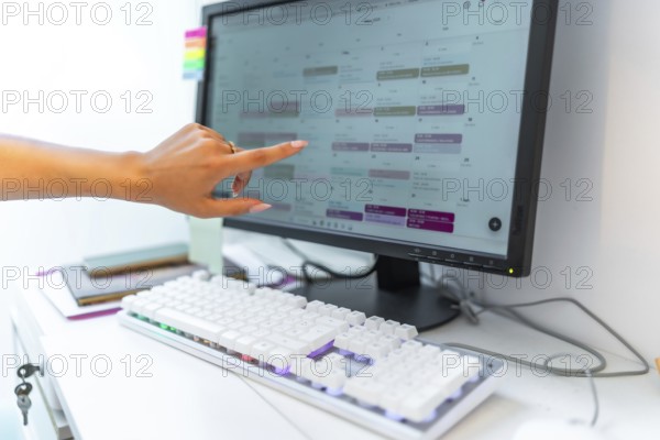 Beautician managing appointments, consulting online schedule on computer in a beauty salon,