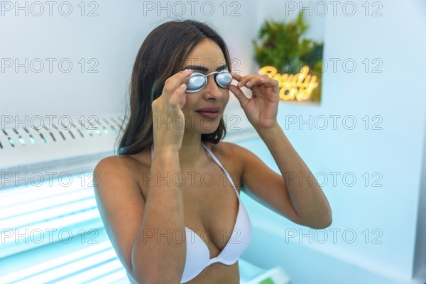 Client putting on protective eyewear preparing for tanning session in a solarium at a beauty center