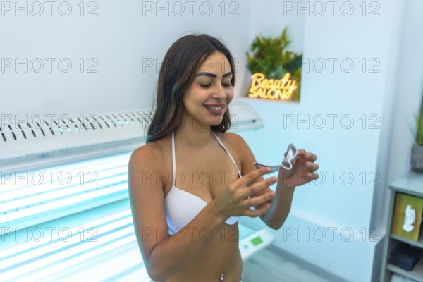 Client preparing for a uv tanning session, adjusting protective eyewear while getting ready in a