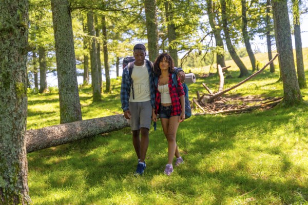 Young couple hiking through a lush forest, enjoying a summer trekking adventure filled with