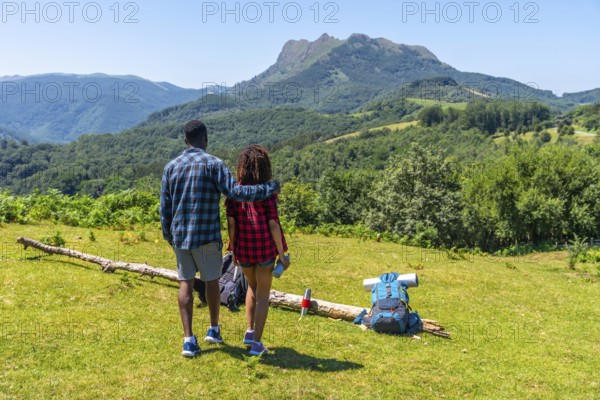 Couple admiring breathtaking mountain landscape during summer hike, enjoying the peace and beauty