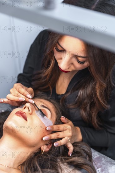 Beautician carefully applying eyelash extensions to a client, enhancing her natural beauty in a
