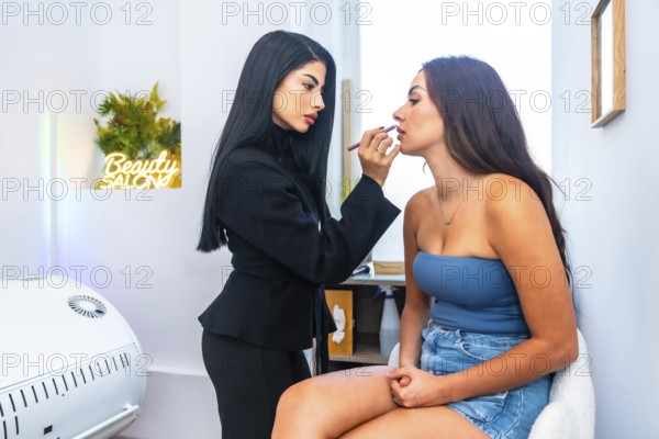 Makeup artist skillfully applying lipstick on a young woman in a modern beauty salon, enhancing her