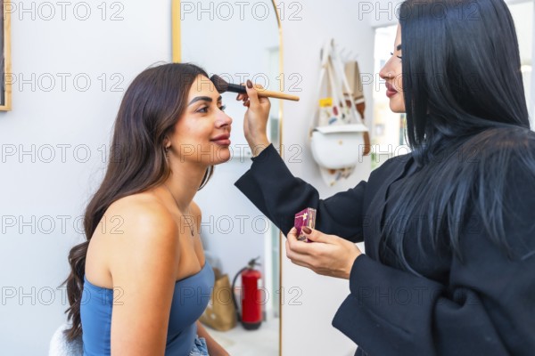 Professional makeup artist applying foundation on a client's face using a brush, enhancing her