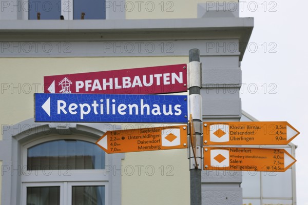 Sign, signpost, pile dwellings, reptile house, arrow, several signposts with distance, writing,