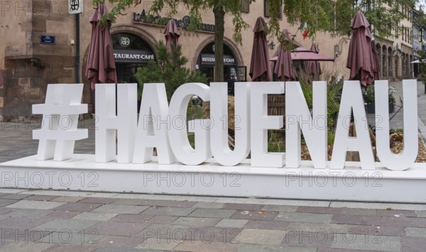 Large lettering in an urban setting with cafés in the background and autumnal flair, Haguenau,