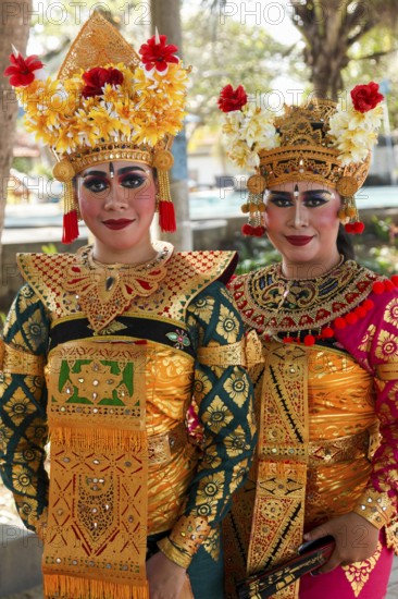 Legong dancers in traditional costumes, wearing makeup, in front of a dance performance in Sanuar,