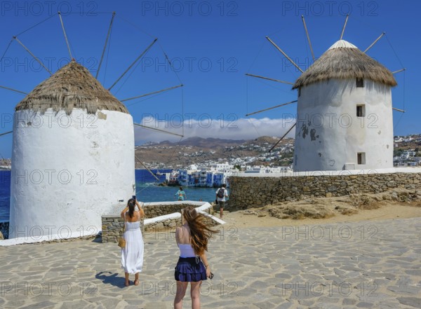 Mykonos, Cyclades, Greece - Tourists photograph the six sixteenth-century windmills lined up on a