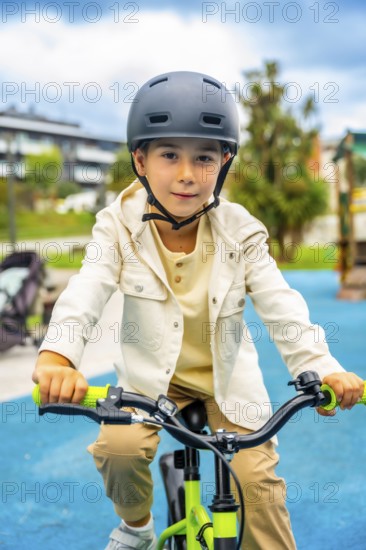 Young boy wearing a helmet rides a bicycle in a park, enjoying a sunny day outdoors while promoting