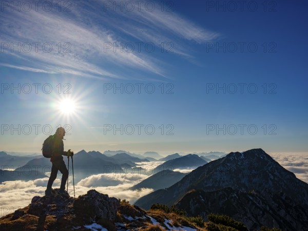 Mountaineer looking at blue-colored silhouette of mountains, fog in the valley, Hochstaufen,