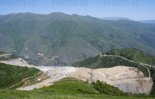 Industrial landscape with mining pit surrounded by green mountains, view of a quarry near Qajaran,