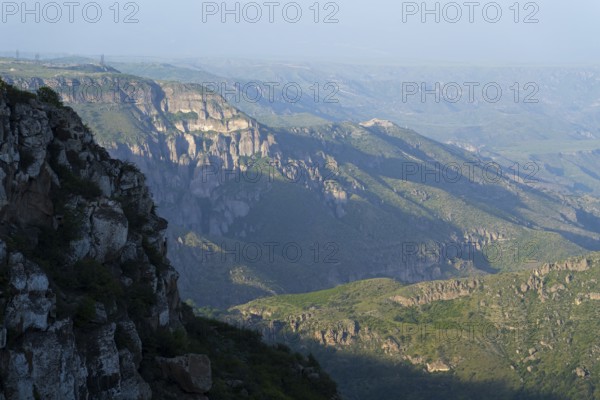 Wide view of rocky gorges and green slopes under a blue sky, view of the Vorotan River valley,