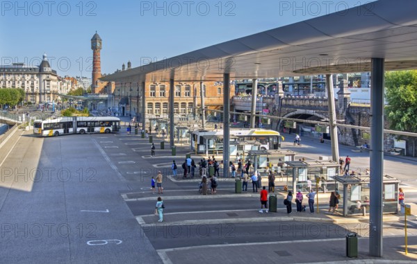 Commuters waiting for transit buses at bus stop of public transport company De Lijn at train