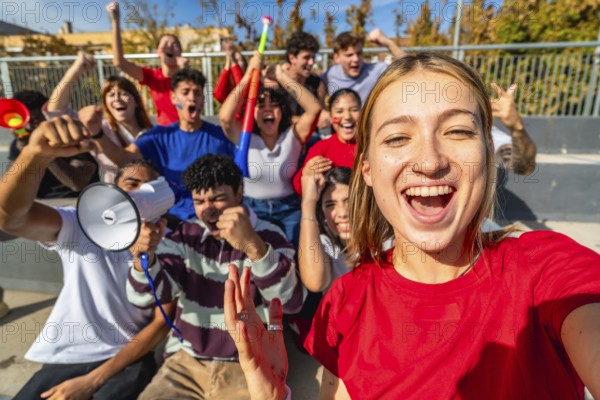 Young diverse fans cheering and taking a selfie in sunny stadium stands, celebrating their team