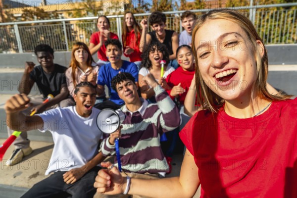 Cheering diverse group of young friends taking a stadium selfie while supporting their team,