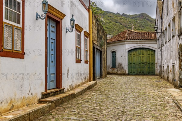 Alley with old colonial-style houses and sunlit cobblestones in the historic city of Ouro Preto in