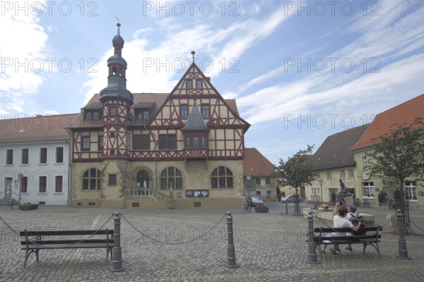Historic town hall built in 1639, couple sitting on park bench, market square, half-timbered house,