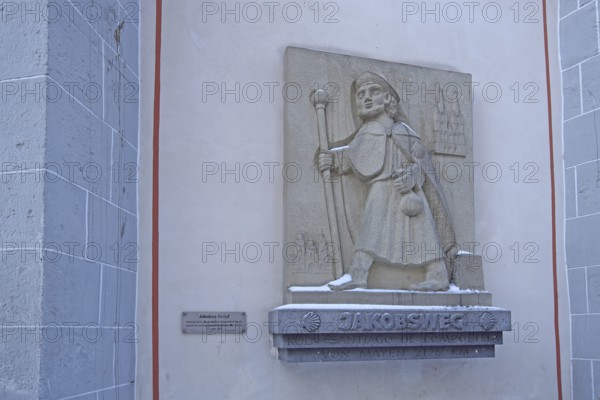 Memorial with pilgrim sculpture and stick on the Camino de Santiago de Compostela via Mayen to