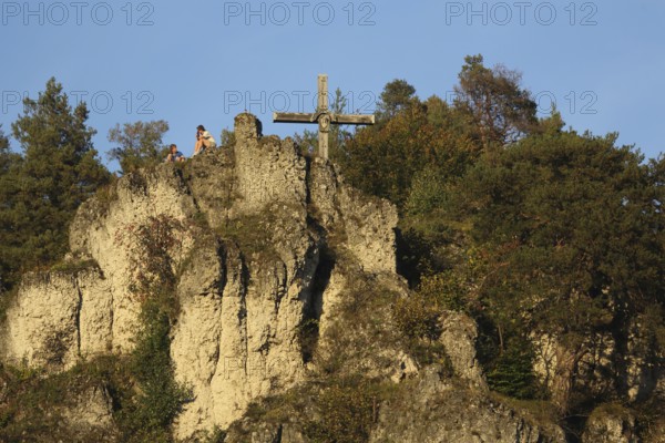 Rocky landscape with summit cross and seated hikers while resting, relaxing, rock formation, rock