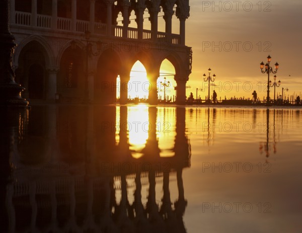 View through the arcades of the Doge's Palace at sunrise on Piazzetta during Acqua Alta, Venice,